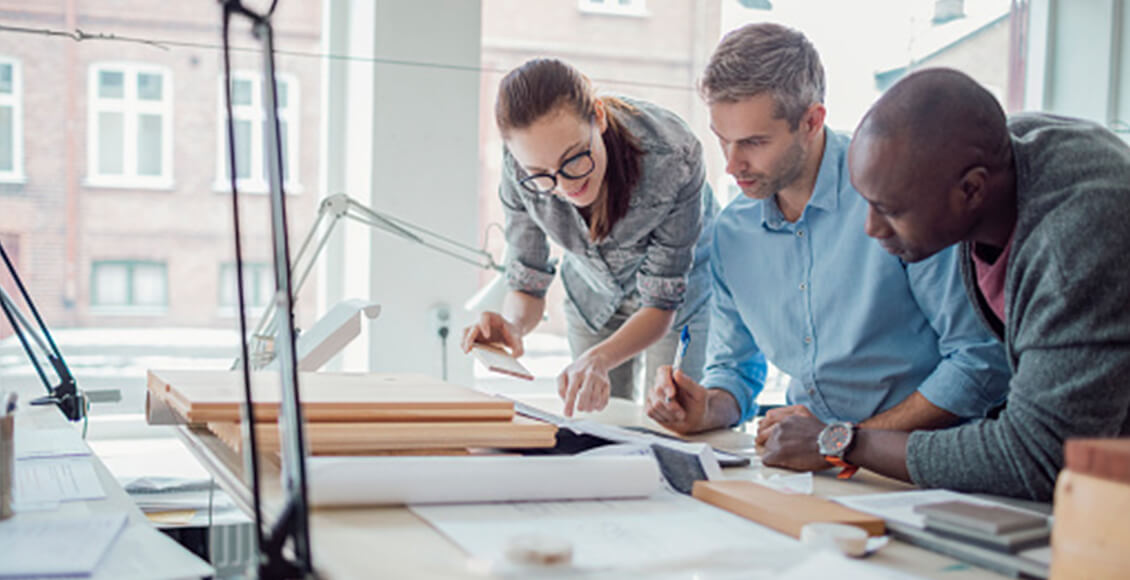 A BIM manager at his desk working with two BIM coordinators on architectural mock-ups.