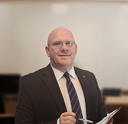 A headshot of a mission critical project manager at Penney Design Group, Aaron Compton, dressed in a suit.