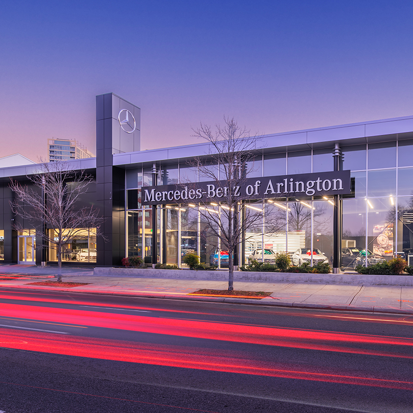 A purple-ish dawn sky overlooking the exterior of Mercedes-Benz of Arlington's sales and service facility.